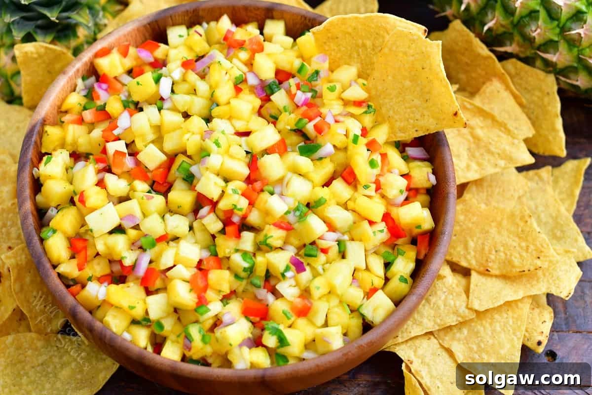 A serving of homemade pineapple salsa, presented in a small bowl, with a generous side of crispy tortilla chips, highlighting its appeal as an appetizer.