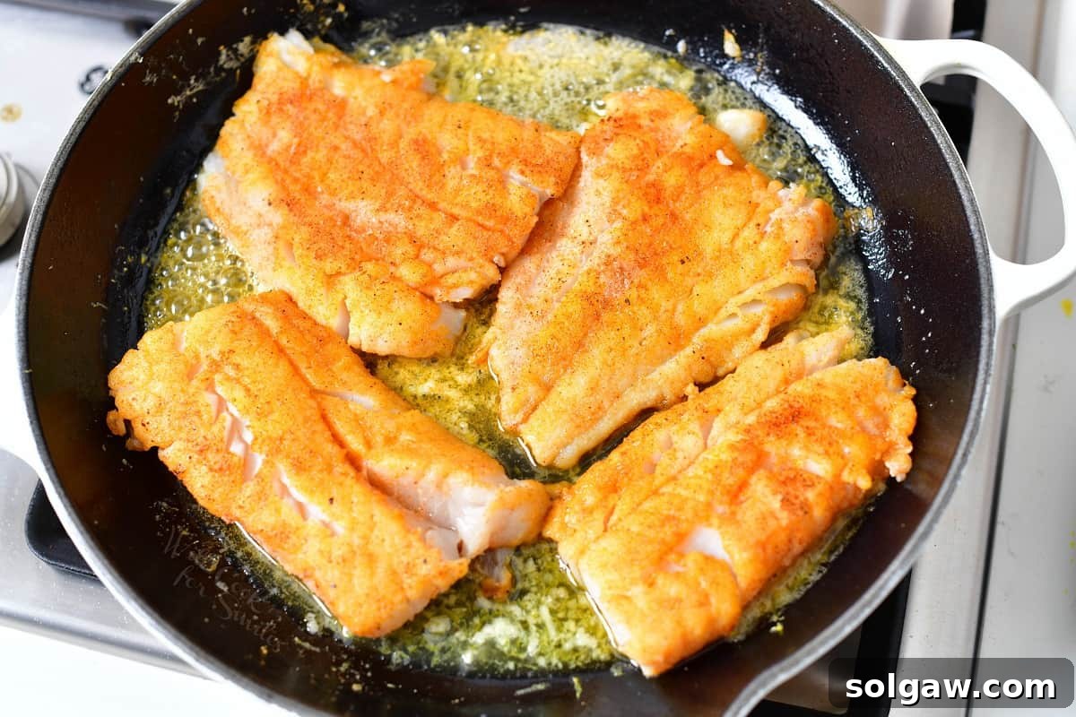 Filets are being cooked in a buttery sauce in the skillet.