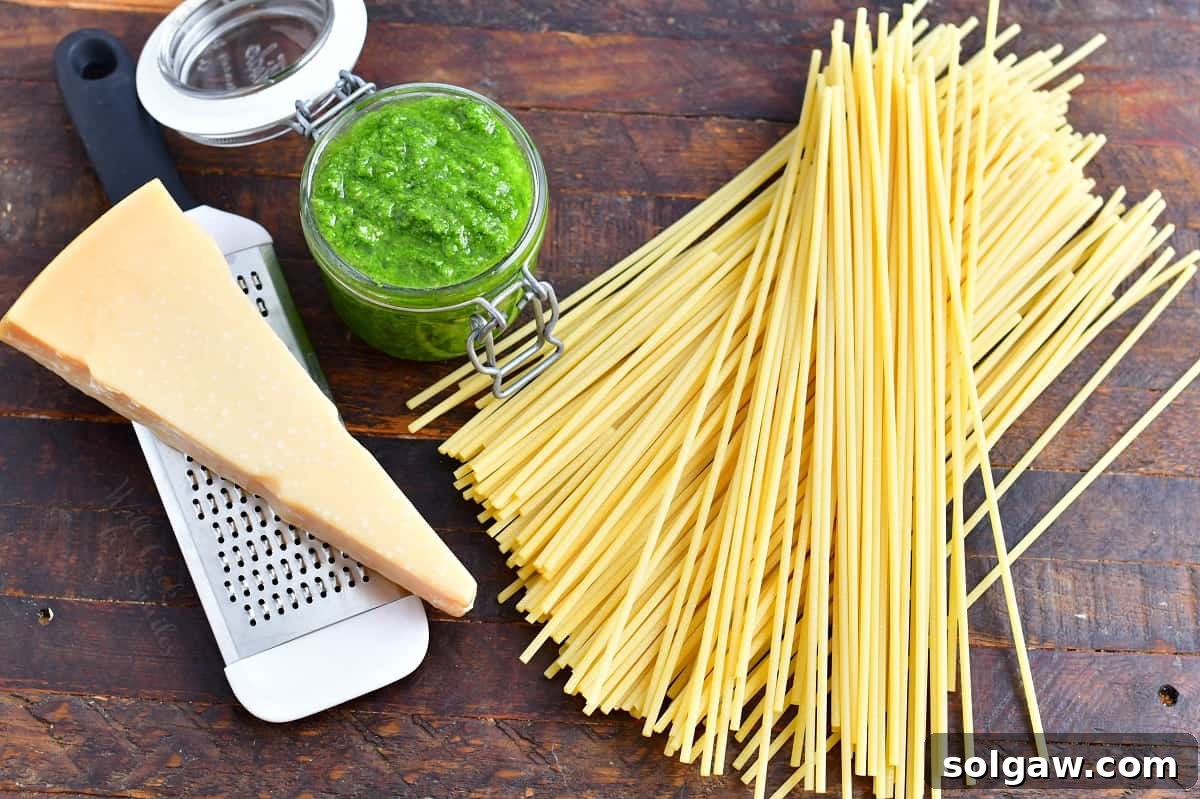 Fresh ingredients for homemade pesto pasta, including bright green basil, whole garlic cloves, golden pine nuts, and a block of Parmesan cheese, elegantly arranged on a rustic wooden surface.