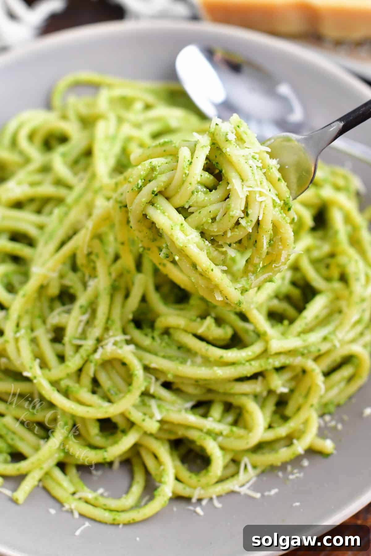 A fork elegantly twirling a perfect bite of creamy pesto pasta, highlighting the smooth, vibrant sauce and perfectly cooked noodles, ready to be savored.