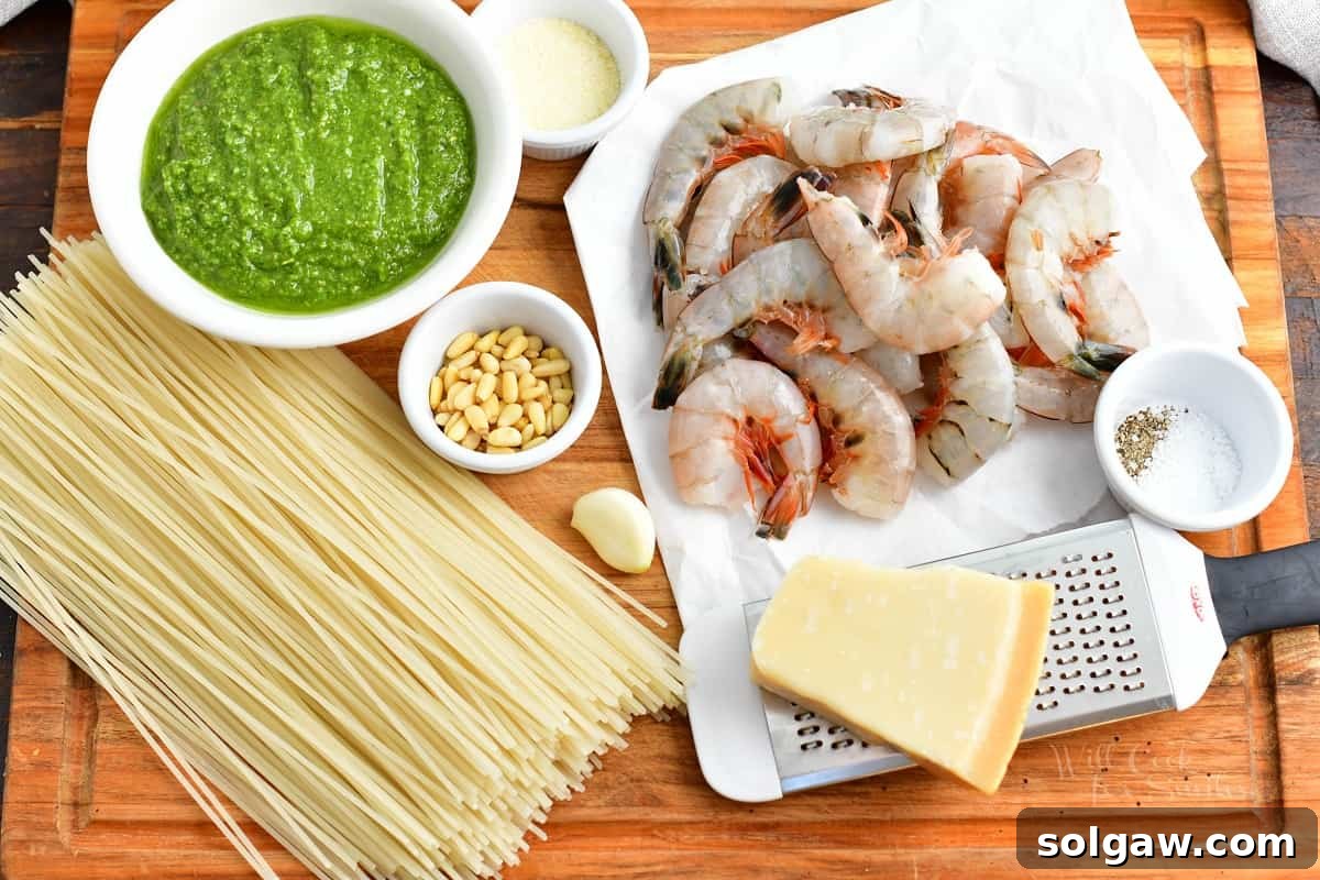 Emerald Pesto Shrimp Pasta 3 The vibrant array of ingredients for homemade shrimp pesto pasta is neatly arranged on a rustic wooden cutting board, showcasing fresh basil, garlic, pine nuts, Parmesan, and raw shrimp.