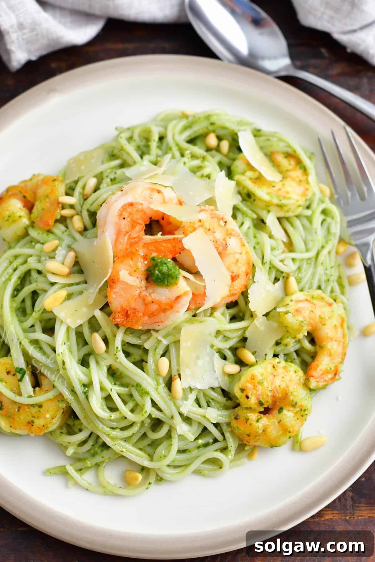 Emerald Pesto Shrimp Pasta 6 A beautifully plated dish of vibrant pesto pasta adorned with plump, pan-seared shrimp, presented on a white plate with fresh garnishes.