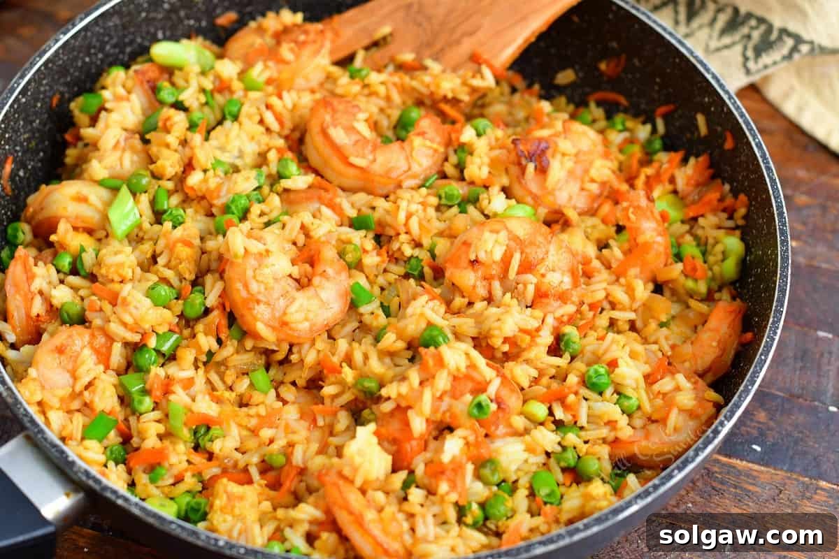 Shrimp fried rice is fully cooked in a black pan.