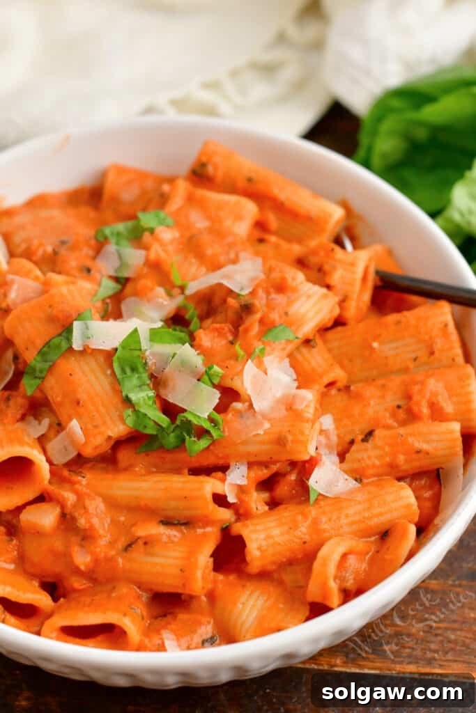 Creamy Tomato Vodka Penne 10 A white bowl filled with pasta is topped with basil and parmesan cheese.