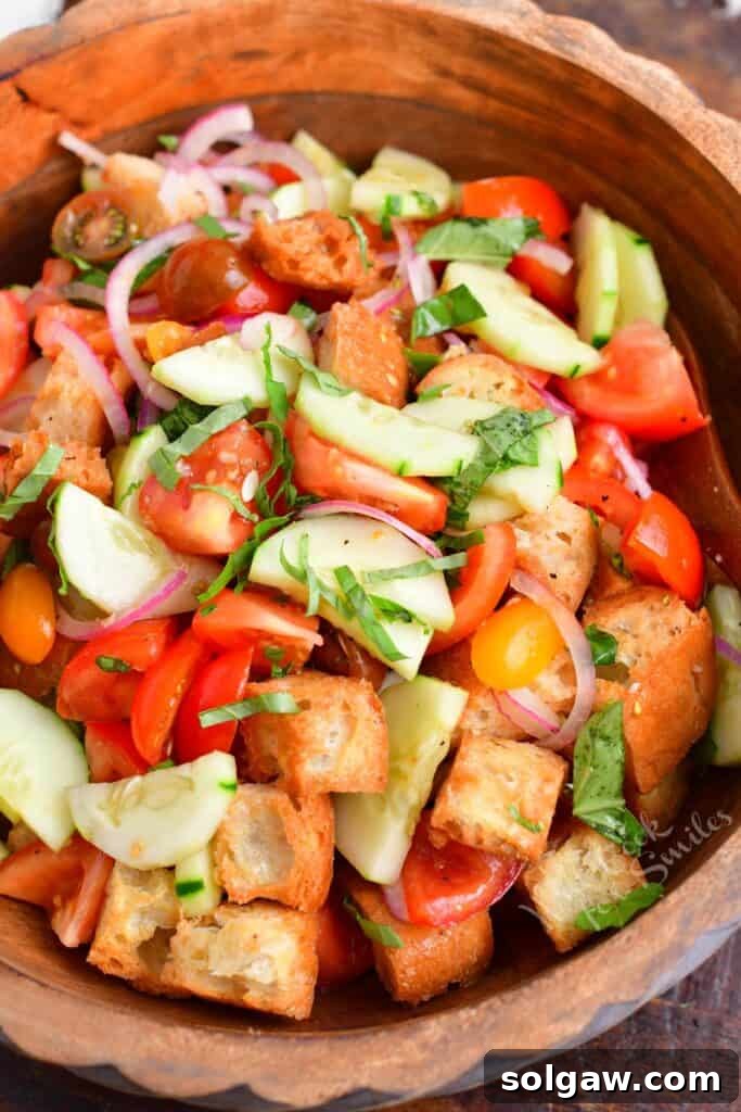 A vibrant Panzanella salad in a wooden bowl, highlighting fresh tomatoes, bread cubes, and basil.