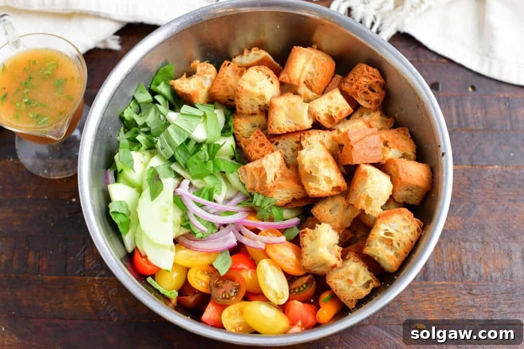 Assorted fresh ingredients for Panzanella salad, including tomatoes, basil, cucumber, and red onion.