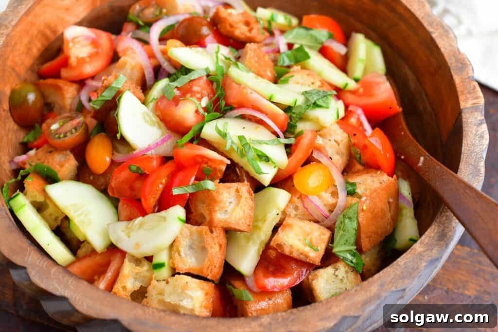 Close-up of Panzanella salad in a wooden bowl, showcasing the textures of bread, tomatoes, and basil.