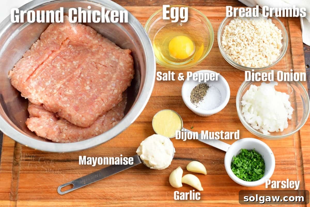 Ultimate Chicken Burgers 3 Labeled ingredients to make chicken burgers on a cutting board, including ground chicken, eggs, breadcrumbs, onion, garlic, parsley, Dijon mustard, and mayonnaise.