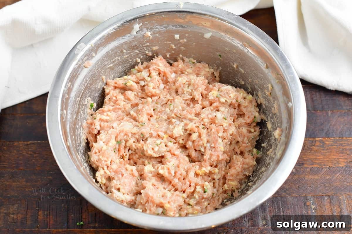 Ultimate Chicken Burgers 4 Mixed ingredients for chicken burgers in a metal mixing bowl, showing the combined ground chicken, herbs, and binders.