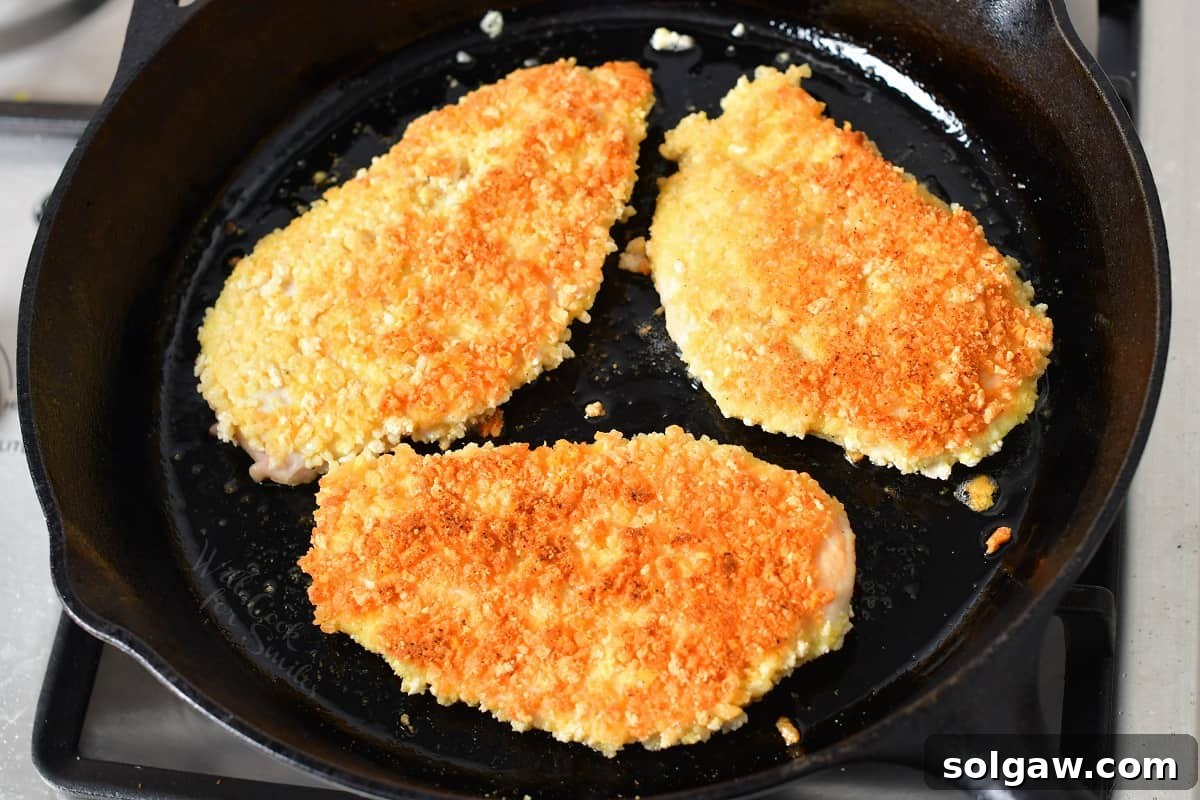 Golden brown chicken is in a black pan.