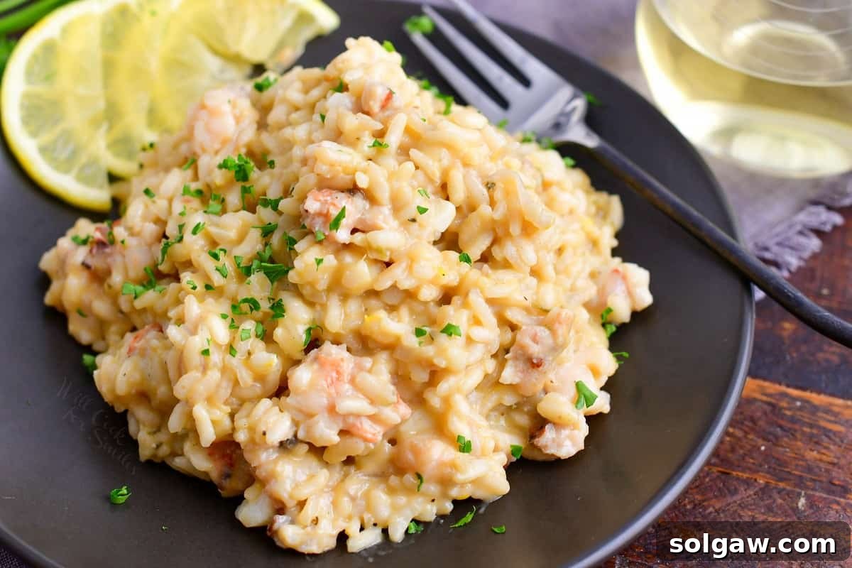 A black plate with a generous serving of lobster risotto.