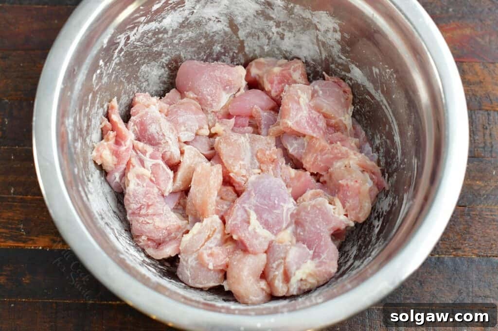 chicken thigh meat tossed in corn starch in a bowl