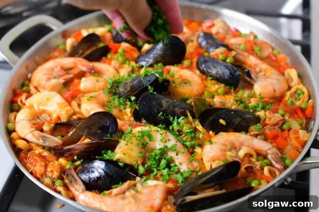A Family's Cherished Paella 11 Freshly chopped parsley is being sprinkled over the top of the finished paella as a garnish, adding color and aroma.