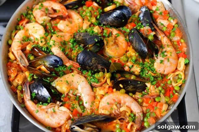 A Family's Cherished Paella 12 The fully cooked paella, garnished with parsley and lemon wedges, is presented in its pan, ready to be served.