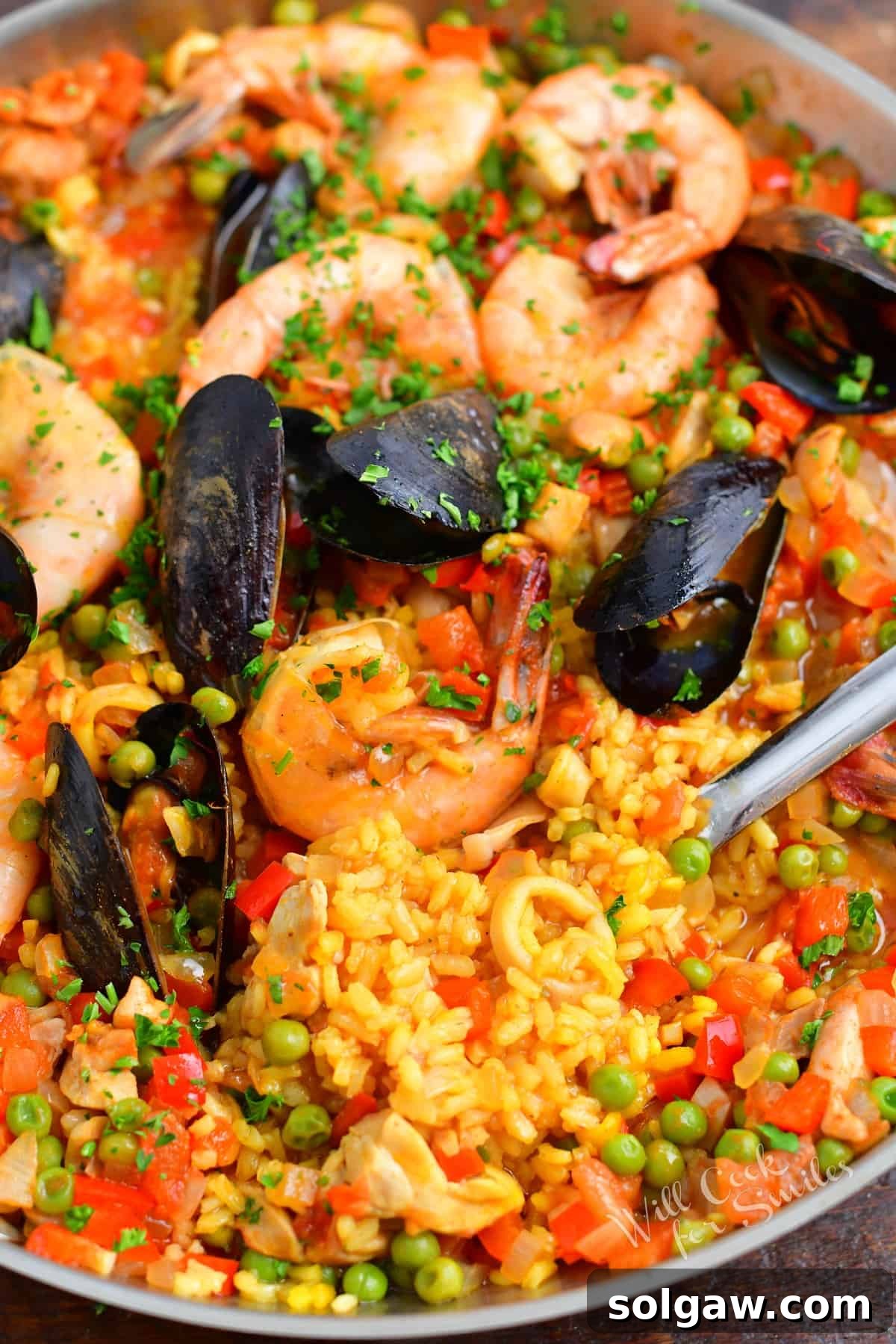 A Family's Cherished Paella 13 A large serving spoon is gently lifting a portion of chicken and seafood paella from the pan, showcasing its rich texture and ingredients.