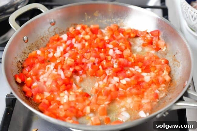 A Family's Cherished Paella 6 Diced tomatoes are being sautéed in a paella pan, forming part of the aromatic sofrito base.