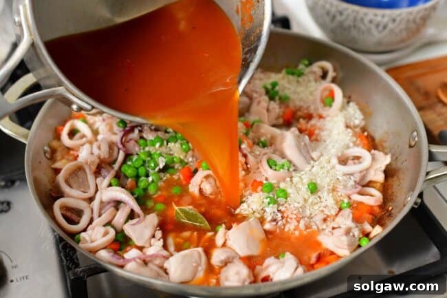 A Family's Cherished Paella 7 Warm chicken stock, infused with saffron and spices, is being poured into a paella pan filled with rice and sautéed vegetables.