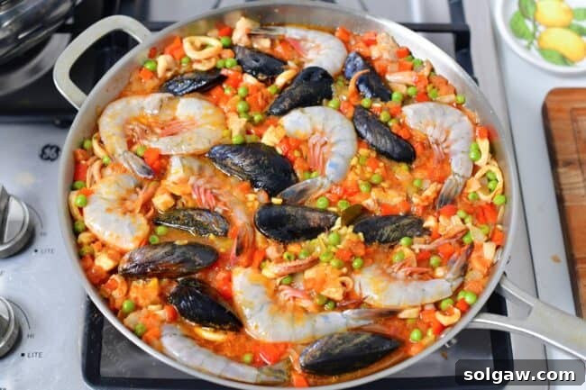 A Family's Cherished Paella 10 Shrimp and mussels are nestled into the paella, cooking alongside the rice, with the mussels just beginning to open.