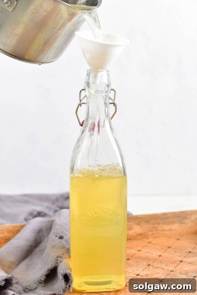 Limoncello is being carefully poured from the pot into a bottle.