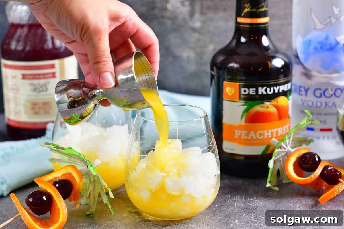 Peach schnapps being meticulously poured into a glass filled with ice, signaling the start of cocktail creation.