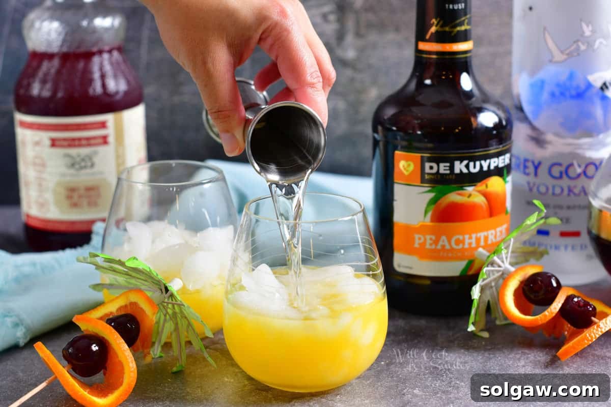 Vodka gracefully being poured into a glass already containing ice and orange juice, layering the cocktail's base.