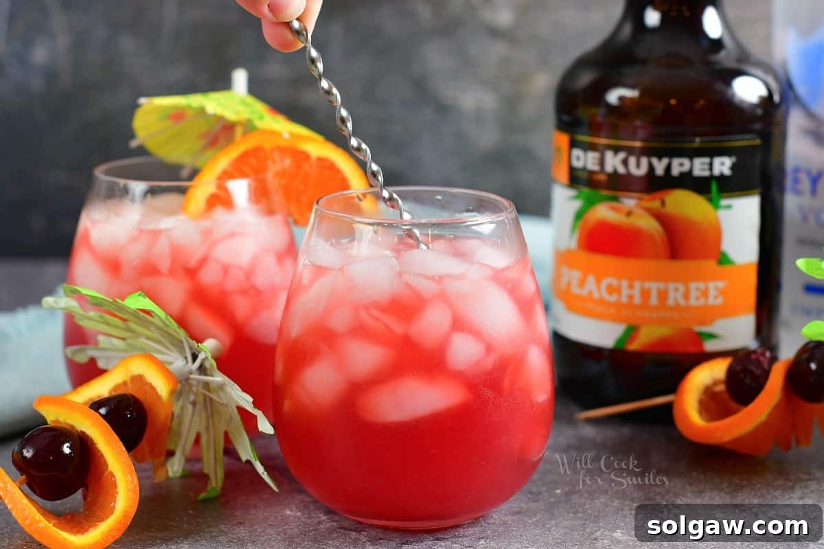 A small bar spoon expertly stirs a cocktail in a glass, ensuring all ingredients are perfectly blended for a harmonious taste.