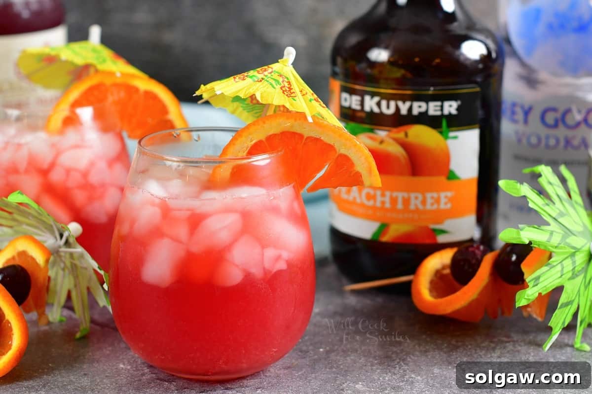 Two vibrant Sex on the Beach cocktails are elegantly displayed beside a bottle of peach schnapps, highlighting a key ingredient.