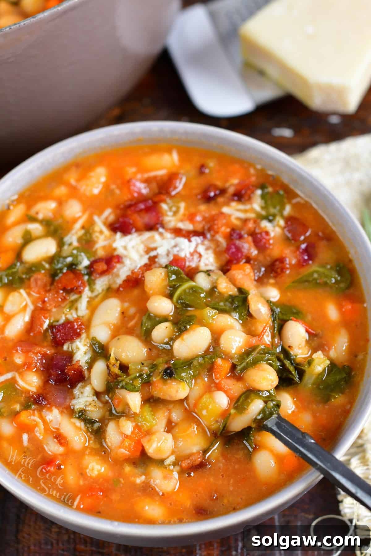 A bowl of white bean soup is presented with a spoon on a countertop.