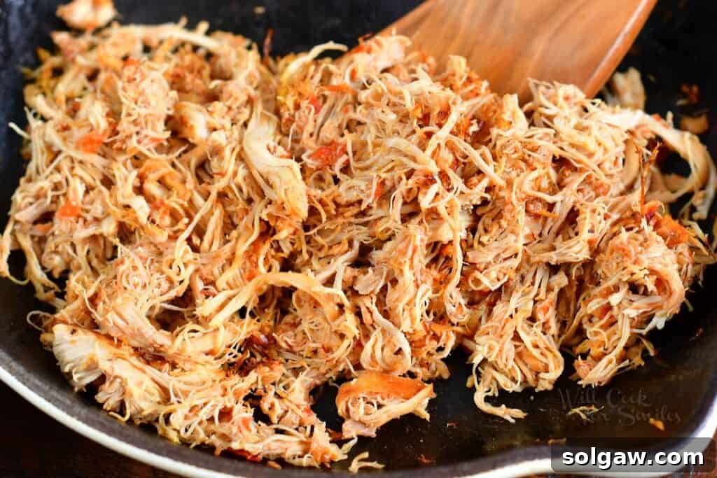 searing shredded chicken in a pan