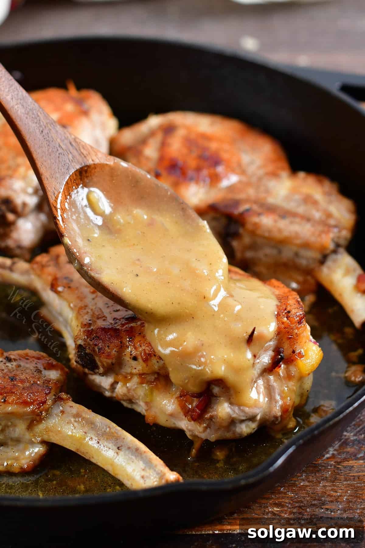 A generous amount of creamy, golden mustard sauce is being artfully drizzled over the beautifully cooked stuffed pork chops, adding the perfect finishing touch and enhancing their appeal.