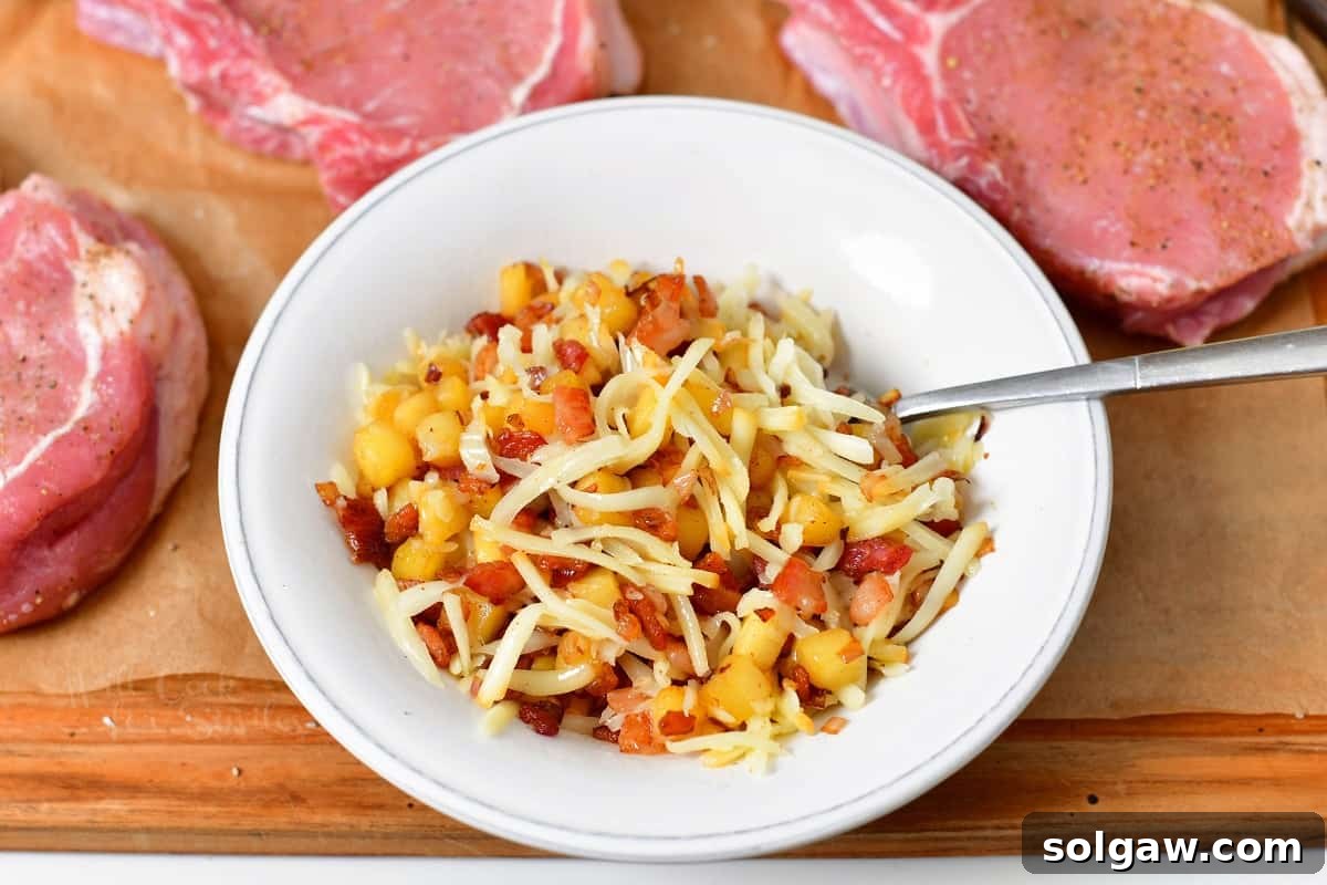 Melted smoked cheddar cheese is carefully stirred into the warm apple and bacon filling in a small white bowl, creating a rich and gooey mixture for stuffing.