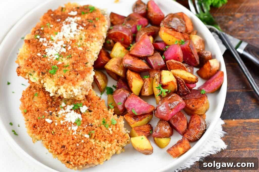 two crispy pork cutlets on a plate with home fries