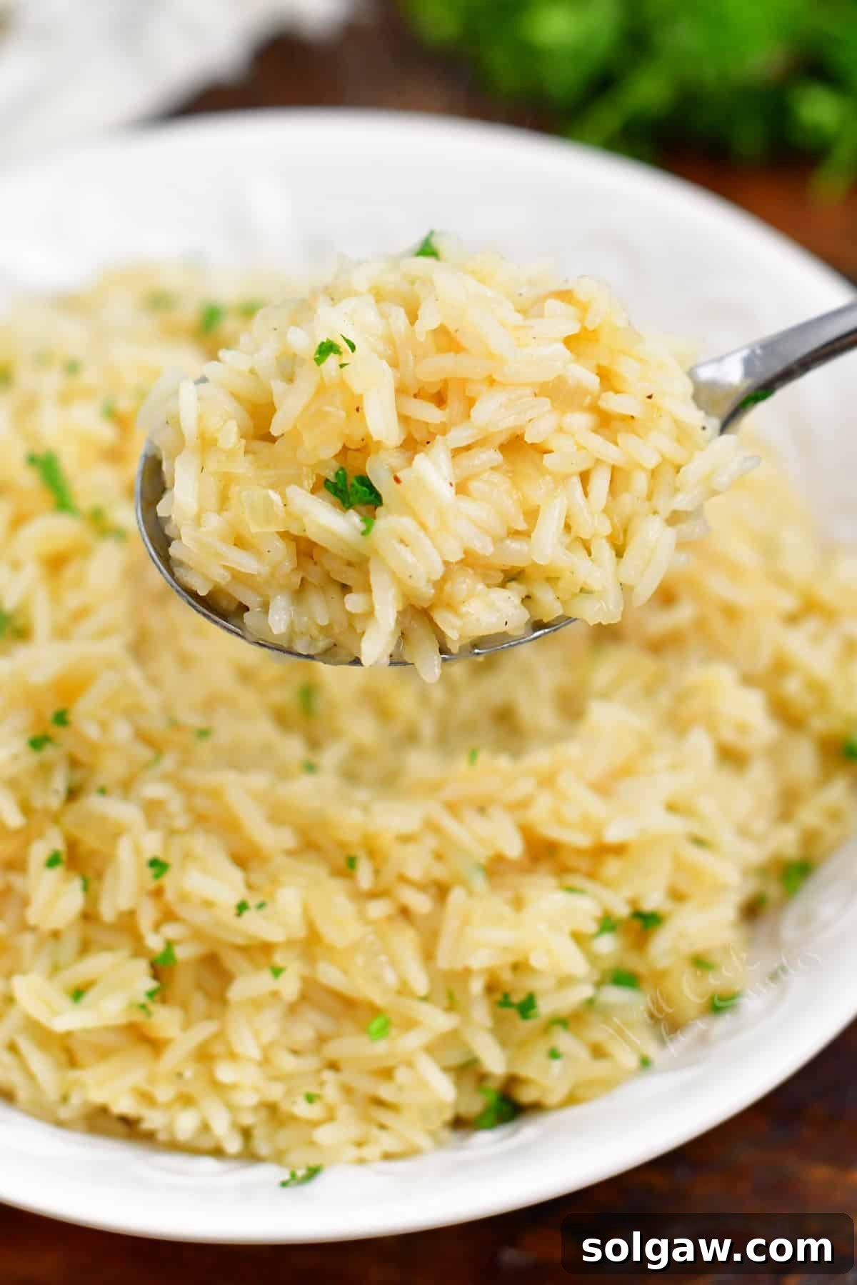 A close-up shot of a spoon scooping up fluffy, perfectly cooked classic rice pilaf from a white bowl, ready to be enjoyed.