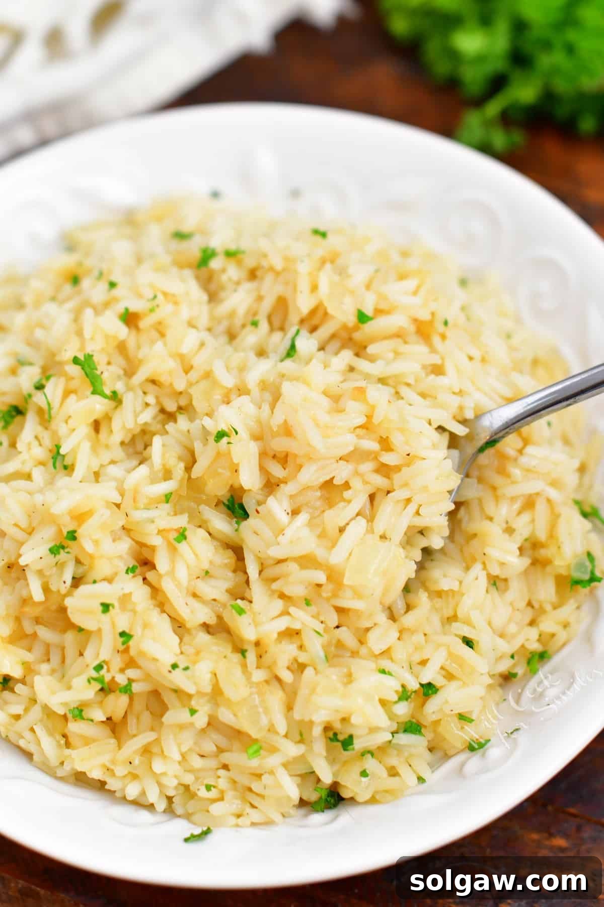overhead image: spoonful of cooked oven pilaf on spoon in white serving bowl