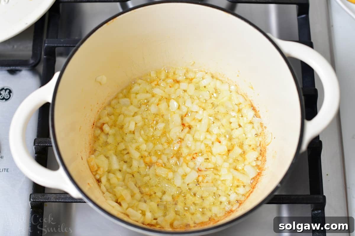 Diced yellow onions sautéing in melted butter in a pot over medium heat, forming the fragrant base of the rice pilaf.