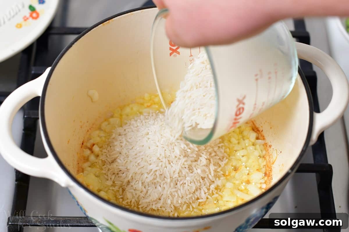 Freshly minced garlic added to sautéed onions in a pot, releasing its fragrant aroma as it cooks briefly.