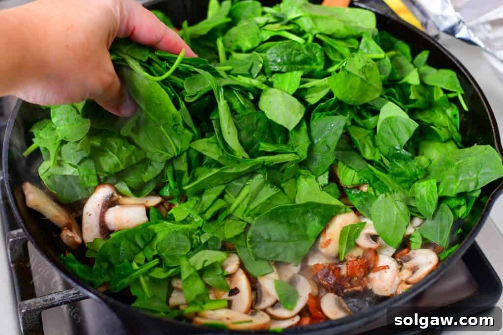 Simple Skillet Frittata 5 adding spinach to bacon and mushrooms in a skillet