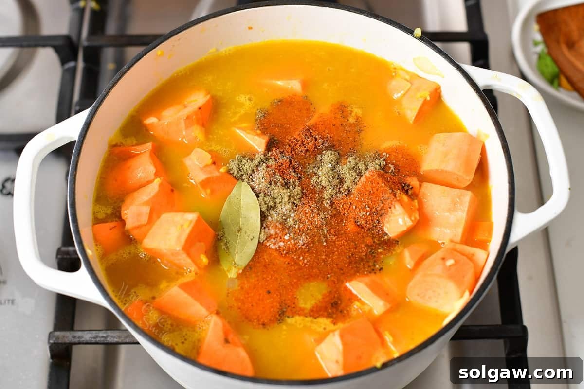 Sweet potatoes covered in broth and spices, simmering in a pot.