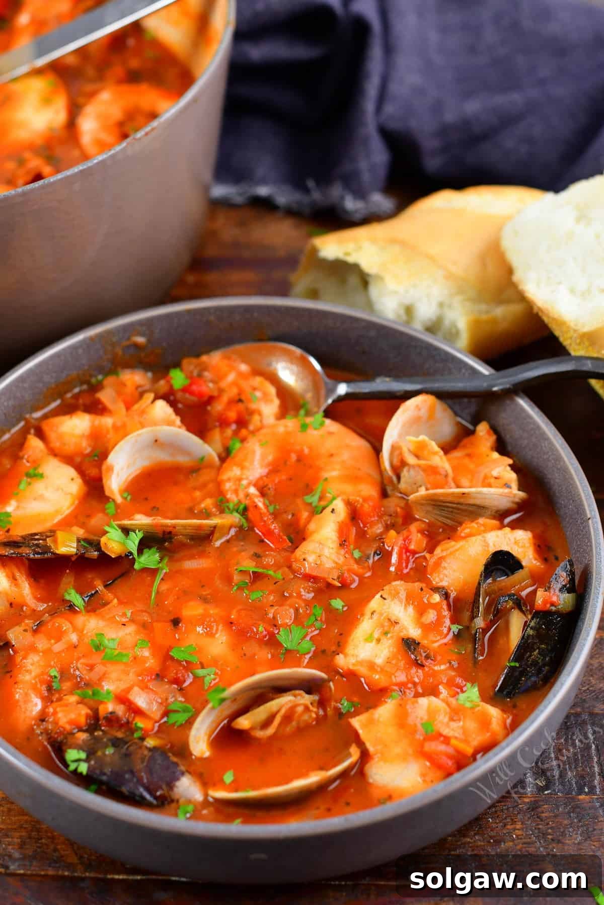 Cioppino in a grey bowl with bread next to it