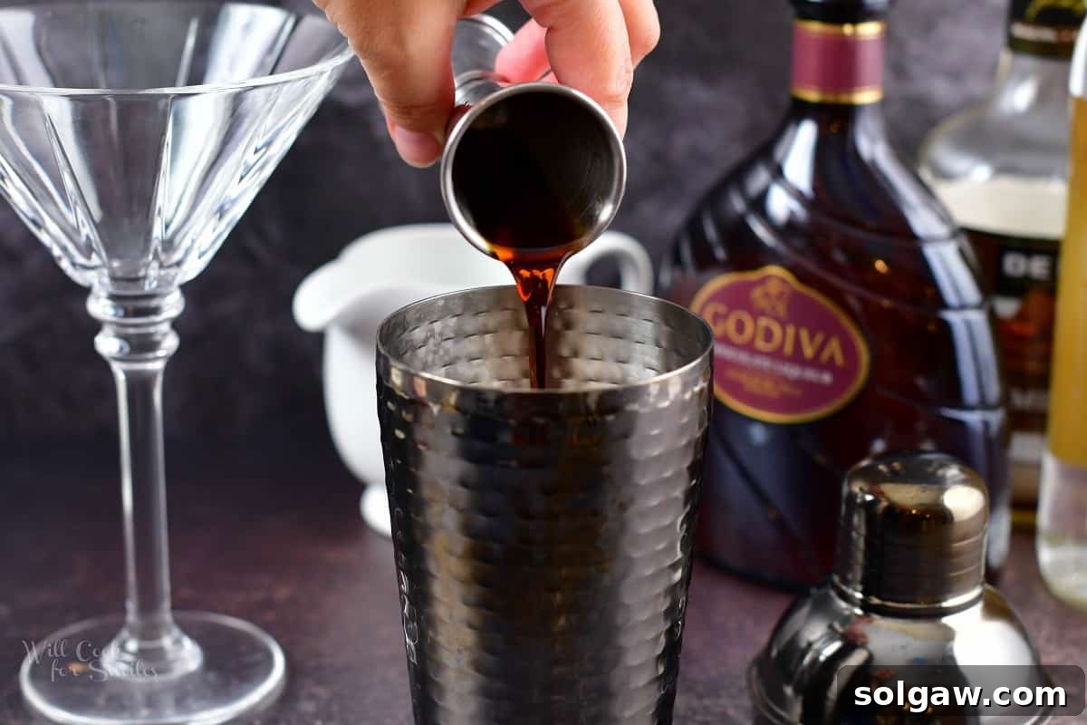adding crème de cocoa to the cocktail shaker