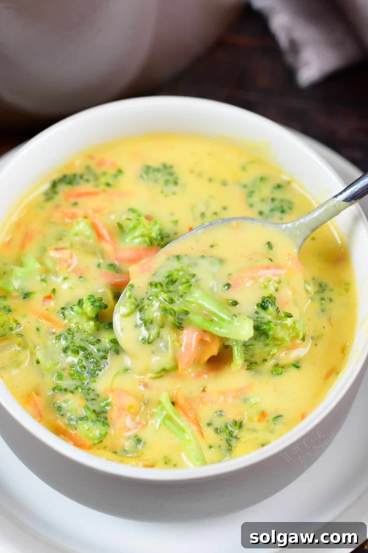 A steaming bowl of creamy broccoli cheese soup, garnished with fresh herbs, ready to be enjoyed.