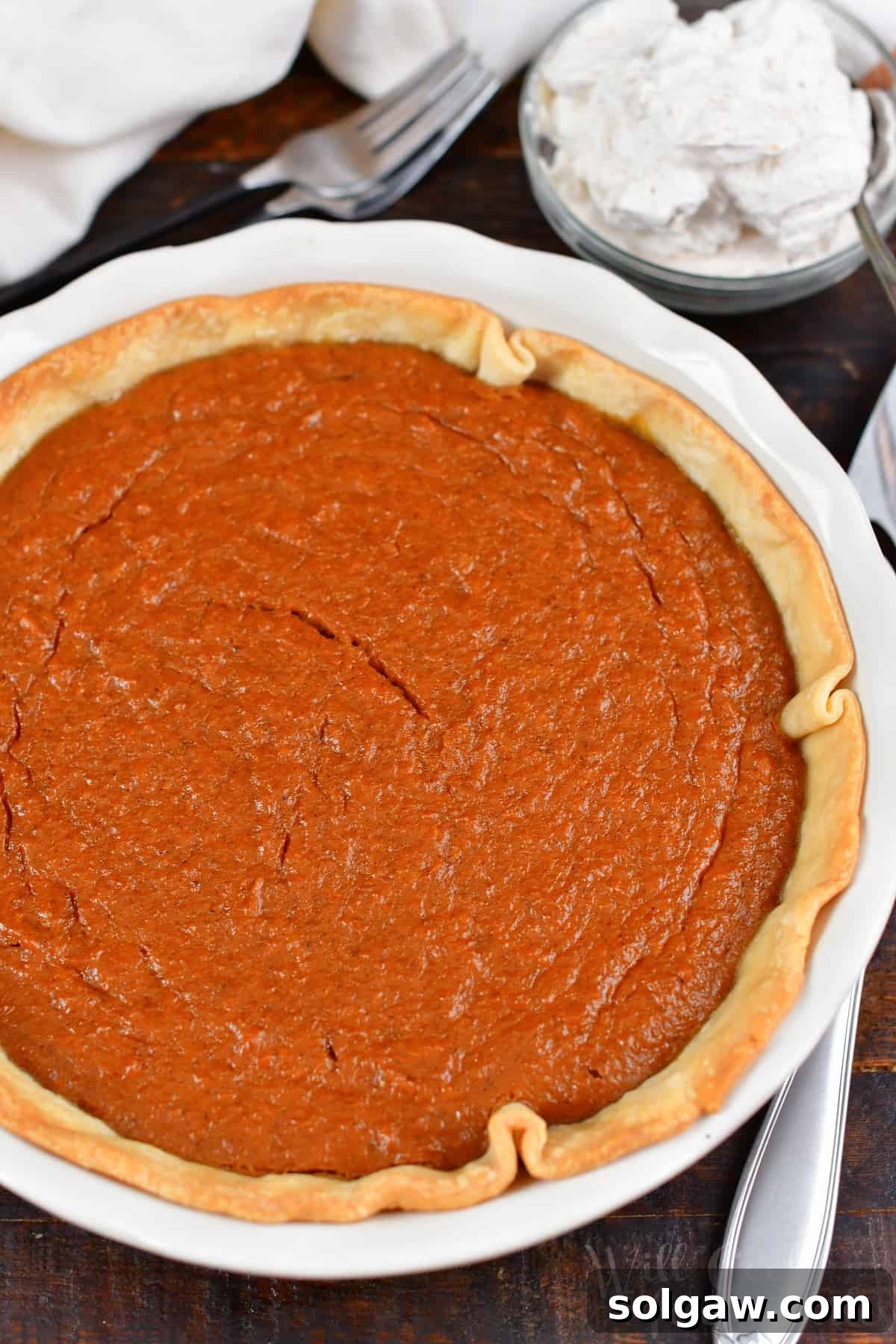 A stunning top view of a whole, beautifully baked Sweet Potato Pie, garnished with cinnamon whipped cream.