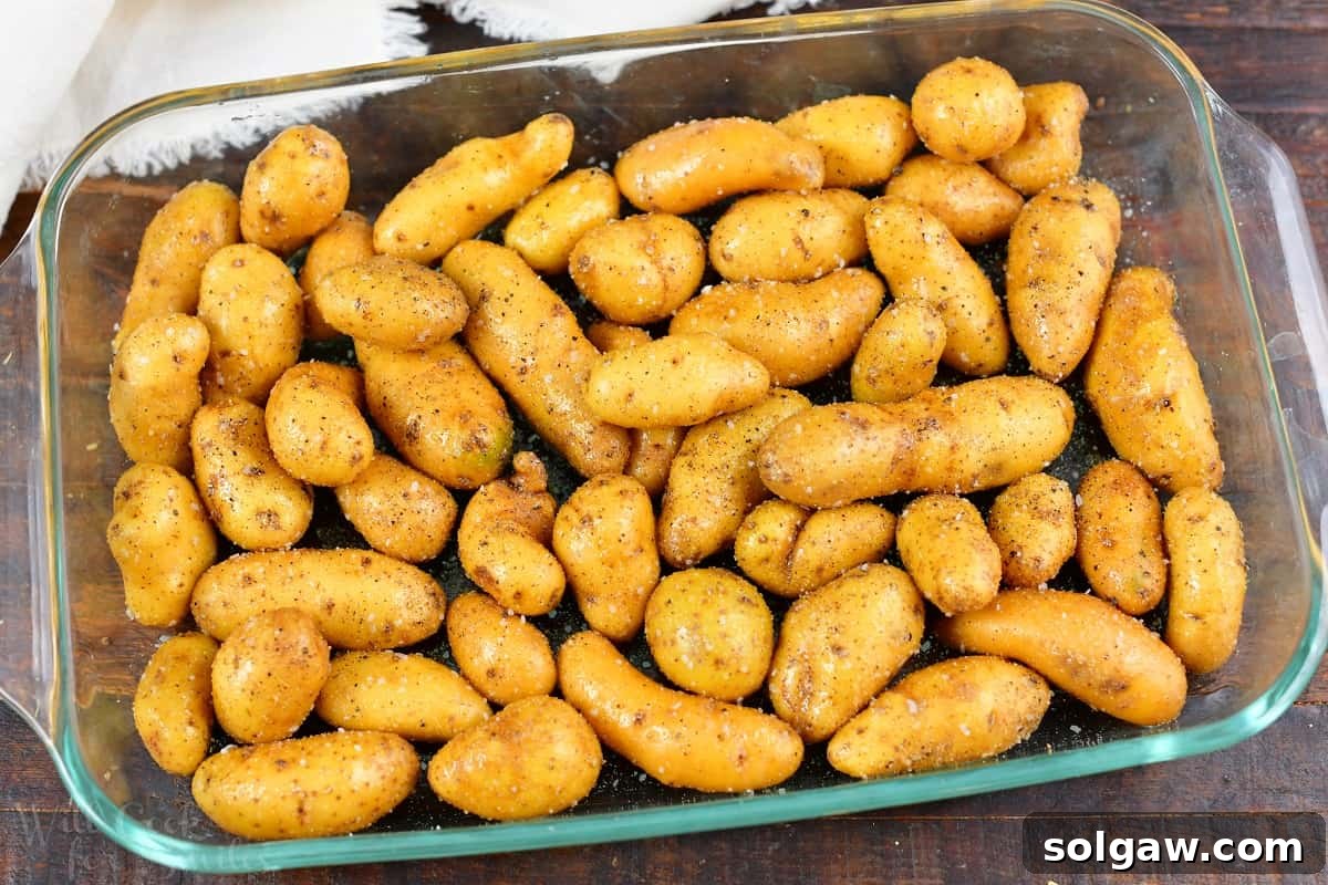 Crispy Golden Fingerling Potatoes 4 Seasoned fingerling potatoes evenly spread in a glass baking dish, ready for roasting