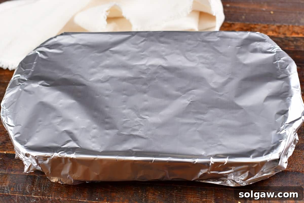 Crispy Golden Fingerling Potatoes 5 Glass baking dish covered tightly with aluminum foil, prepared for the initial phase of roasting