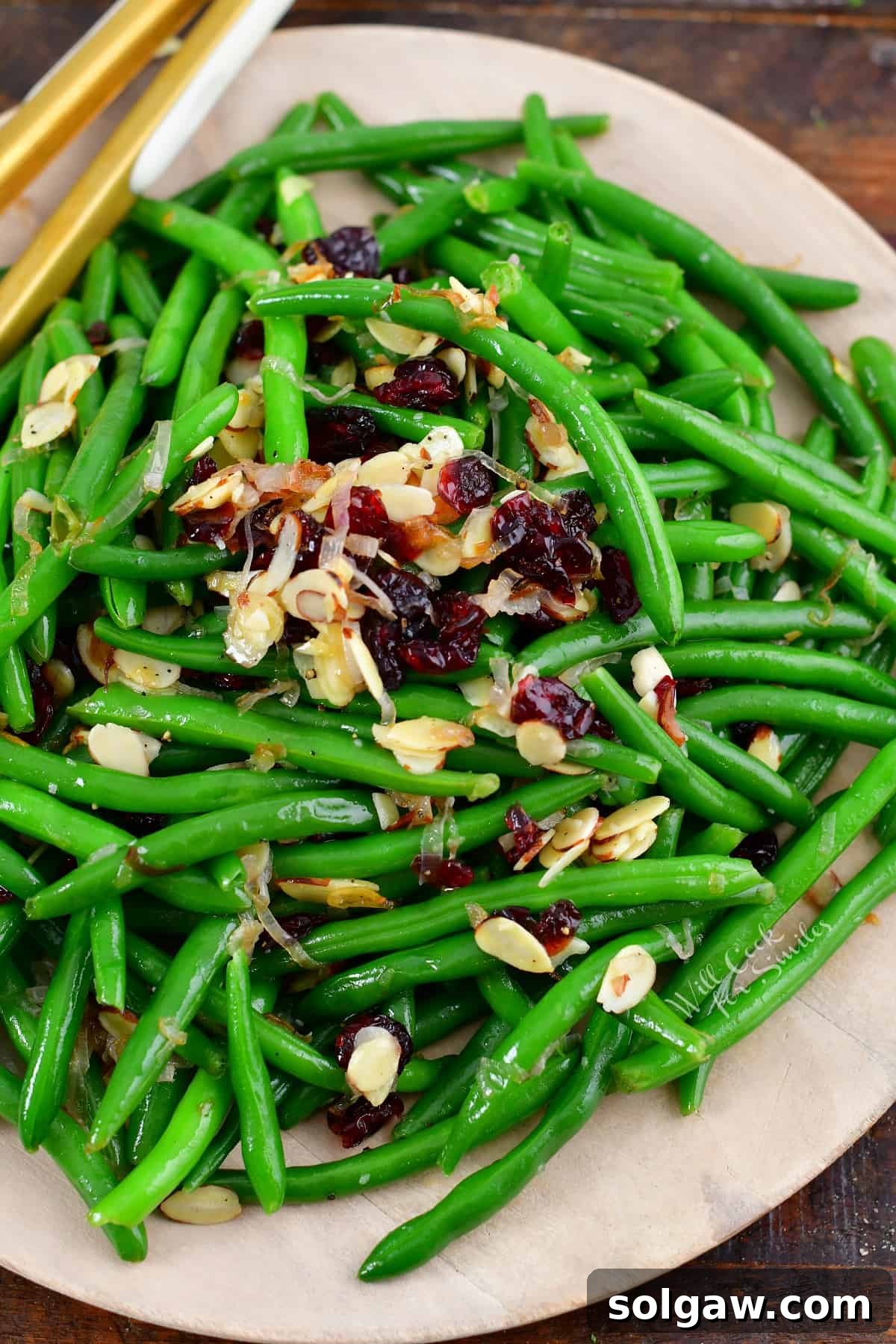 Top view of vibrant sautéed green beans garnished with dried cranberries and toasted almonds, ready to serve.