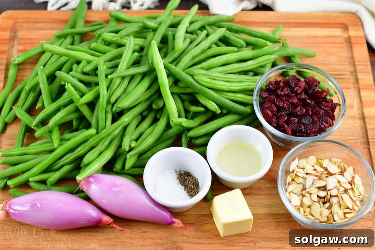 A collection of fresh ingredients for sautéed green beans, including green beans, butter, shallots, almonds, and dried cranberries, neatly arranged on a wooden cutting board.