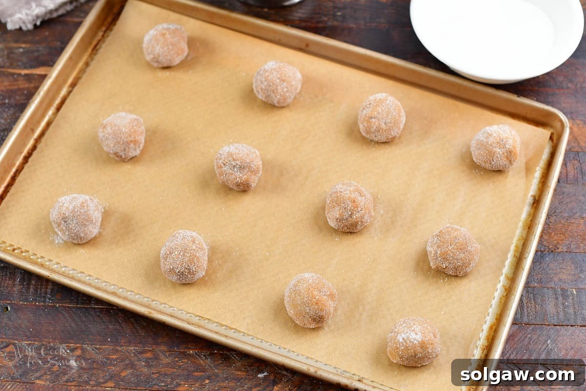 balls of cookie dough covered in sugar on the baking sheet