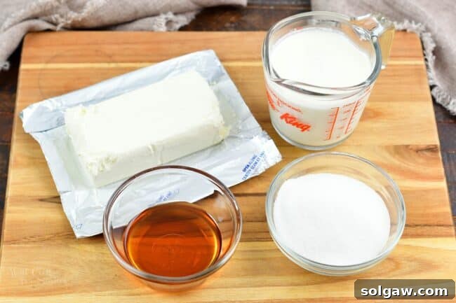 Ingredients for maple cream cheese frosting, including cream cheese, heavy cream, maple syrup, and powdered sugar, arranged neatly.