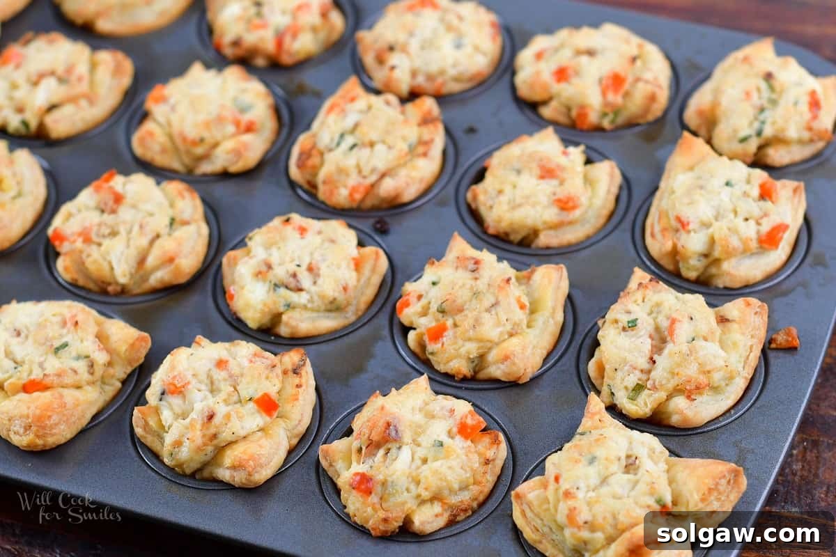 Freshly baked golden brown crab puffs arranged neatly in a mini muffin baking pan, ready to be served.