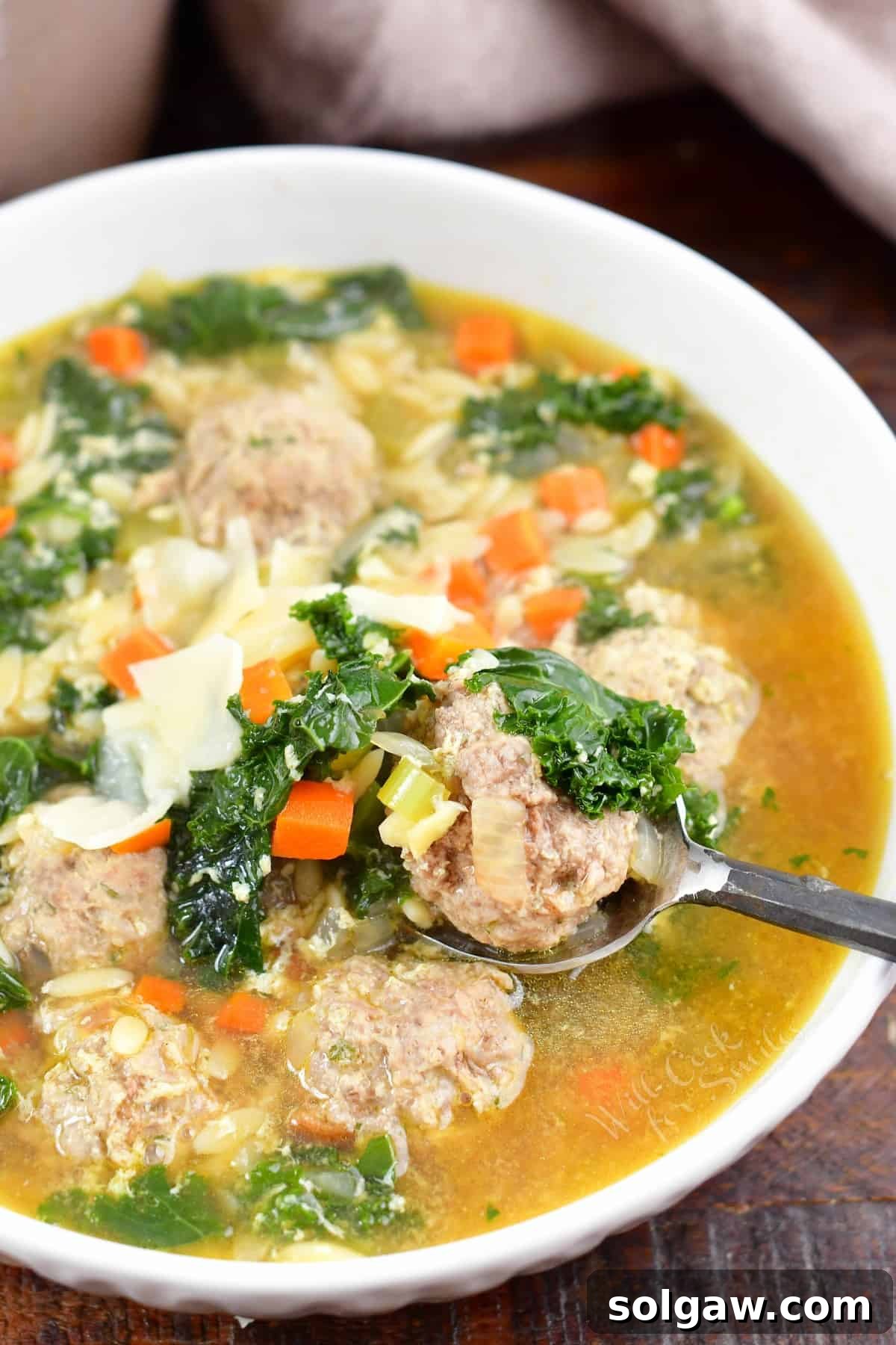 A close-up of a serving of Italian Wedding Soup with meatballs and greens.